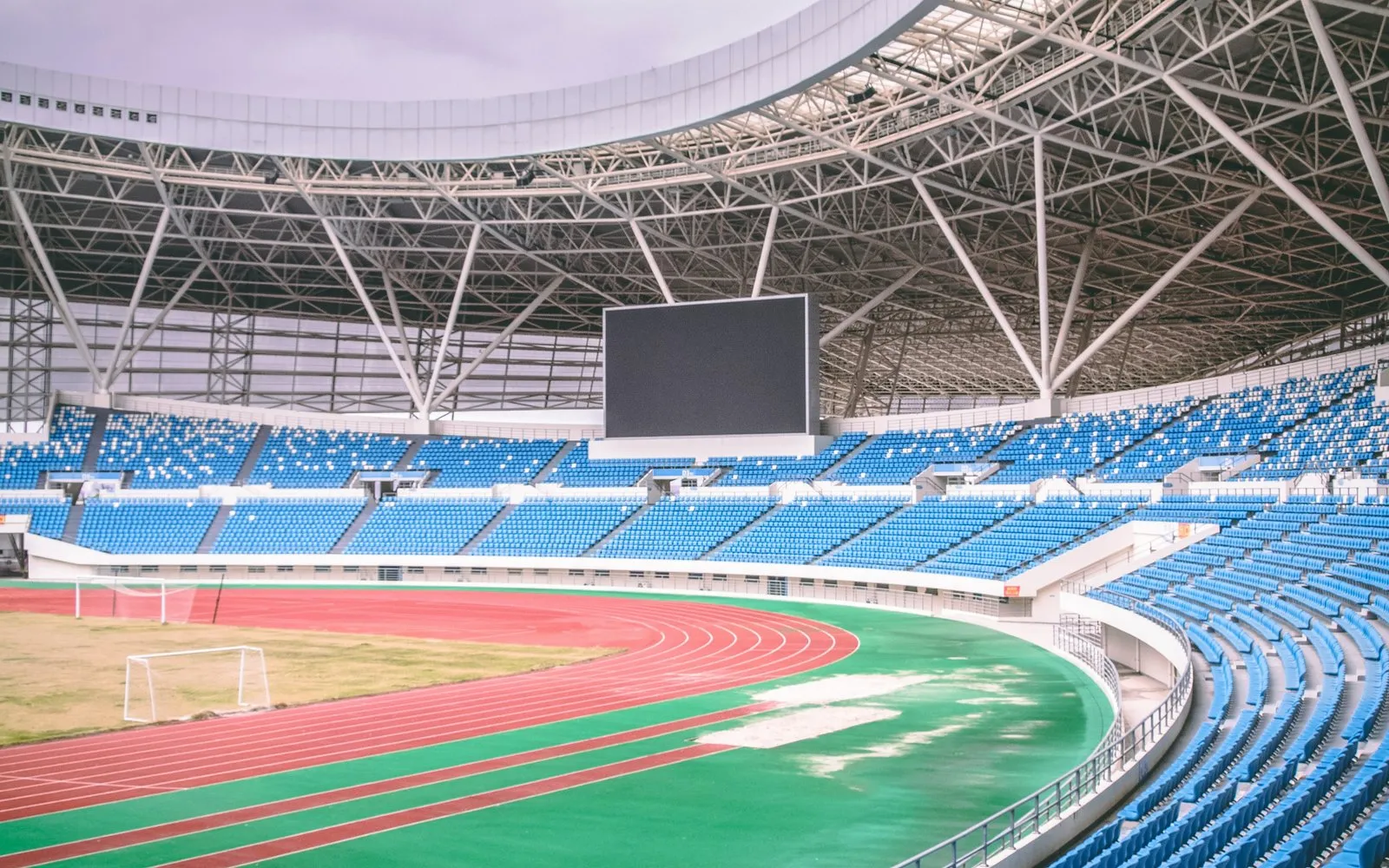 An empty modern stadium with tiered blue seating and a running track